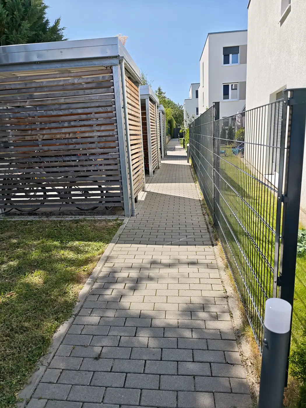 Gepflegter Weg entlang der Fahrradunterstände einer Wohnanlage