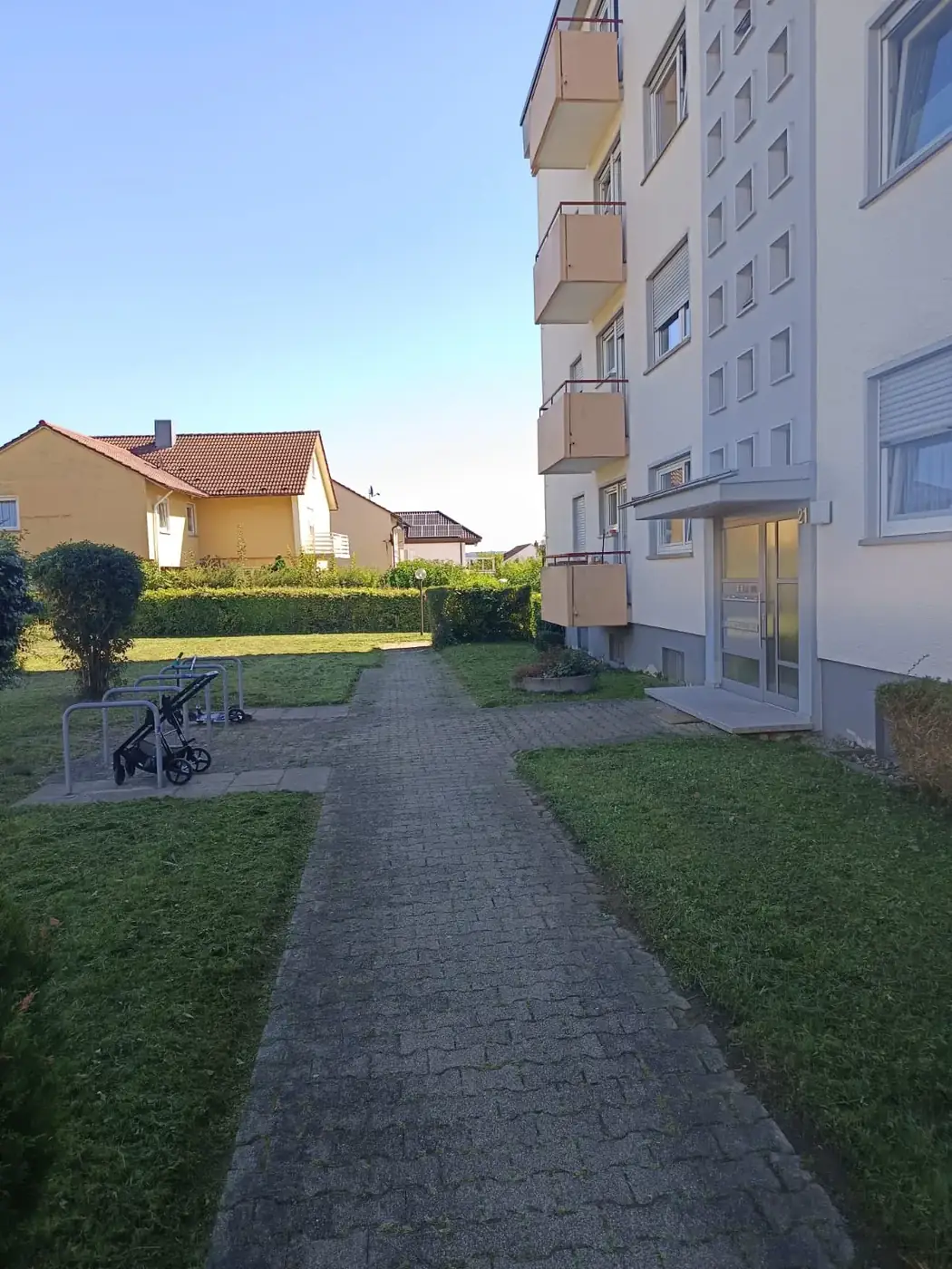Gepflegte Außenanlage einer Wohnanlage mit Weg und Rasenflächen